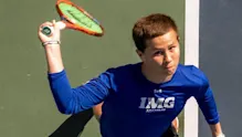 Male tennis player preparing to serve, captured from an overhead angle on the court.