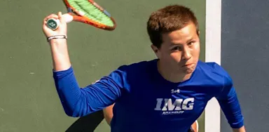 Male tennis player preparing to serve, captured from an overhead angle on the court.