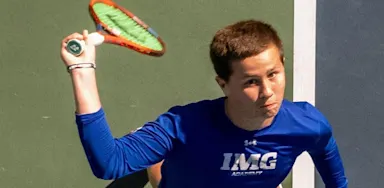 A tennis player raises his racket while preparing a shot.