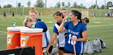 Athletes refill drinks from coolers during a break on the field.