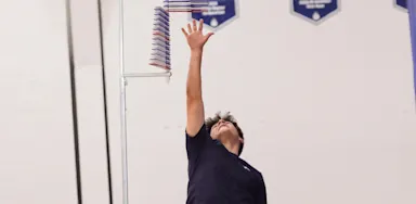 An athlete reaches upward toward a vertical-jump measuring device.