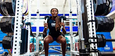 An athlete performs a squat with weights in a gym.