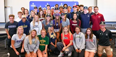 Group of IMG Academy student-athletes wearing college apparel, celebrating their recruitment to various NCAA programs across multiple sports.