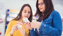 Mother and teenage daughter in a store aisle reading a product label or supplement information, emphasizing parental guidance in nutrition.