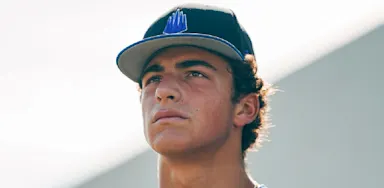 A baseball player wearing a team cap looks into the distance.