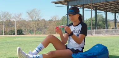 Female student reading the nutrition label on a protein bar.