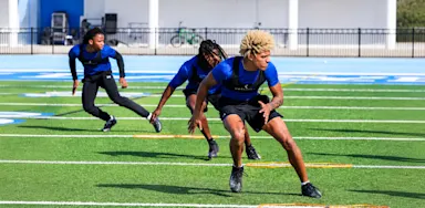 Athletes run an agility drill on a marked field.