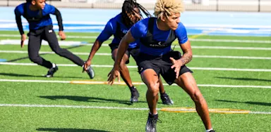 Males on field doing agility drills.