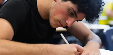 Male student taking notes.