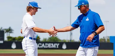 Baseball coach and student-athlete shaking hands on the field at IMG Academy, symbolizing the connection and communication central to the college recruiting process.