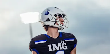 A helmeted football player looks across the field.