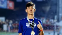 Confident male IMG Academy athlete displaying a gold medal, symbolizing hard work, discipline, and success.