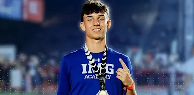 Confident male IMG Academy athlete displaying a gold medal, symbolizing hard work, discipline, and success.
