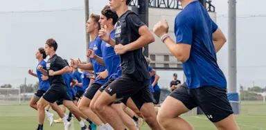 Group of male and female athletes running speed drills.