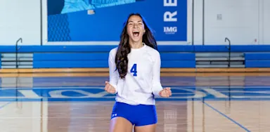 A volleyball player celebrates on an indoor court.