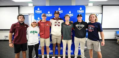 Group of IMG Academy student-athletes in college gear celebrating commitments to NCAA and NAIA programs, representing different collegiate athletic divisions.