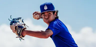 A young baseball player extends his glove while preparing to throw.