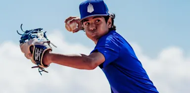 IMG Academy baseball pitcher in a blue uniform throwing a ball during a confidence-building drill.