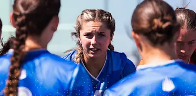 IMG Academy female athlete speaking to teammates during a team huddle, demonstrating leadership, focus, and communication.