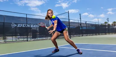 A tennis player tracks an approaching ball while preparing a racket swing on an outdoor court.
