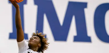Basketball player reaching for a dunk during a game at IMG Academy.
