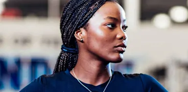 Focused female athlete standing confidently in a training facility, wearing an IMG Academy shirt.