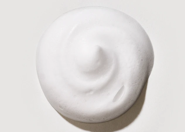 Foamy swirl of curling mousse dispensed in front of a white background.