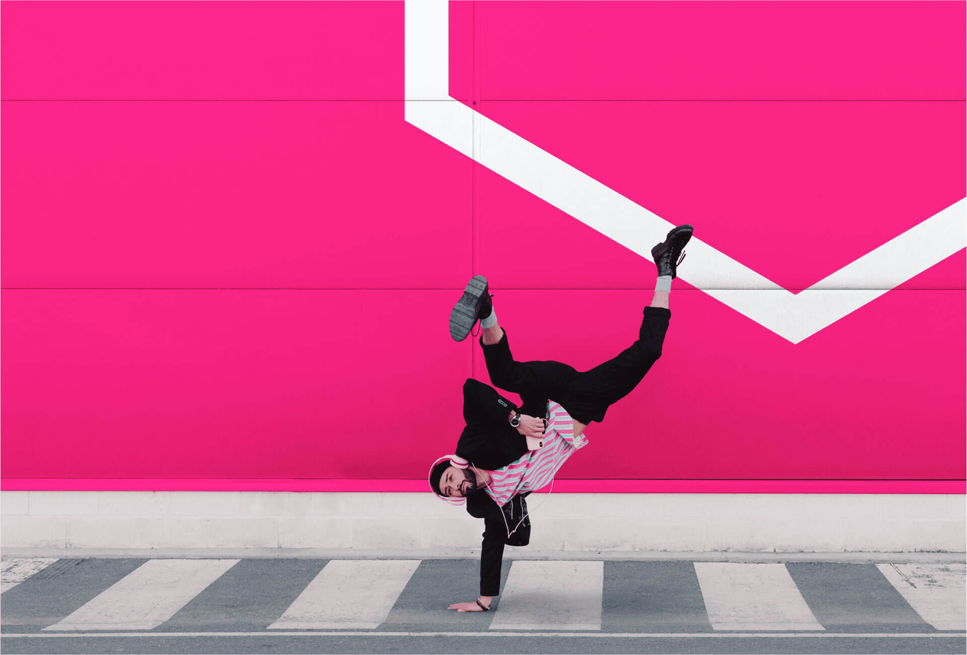 Image of a man break dancing on a crosswalk with pink background with white graphic elements.