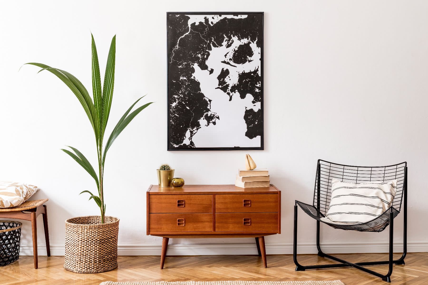 Room with a wooden furniture, a chair, a plant and a painting.