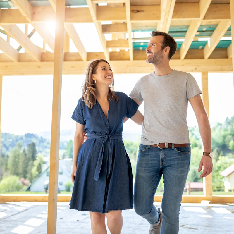 A couple walks through the frame of their unfinished cottage