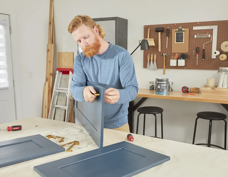 A man reattaches cabinet hardware