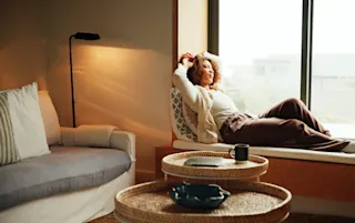 Image of a woman relaxing and reading in a calming, living room.