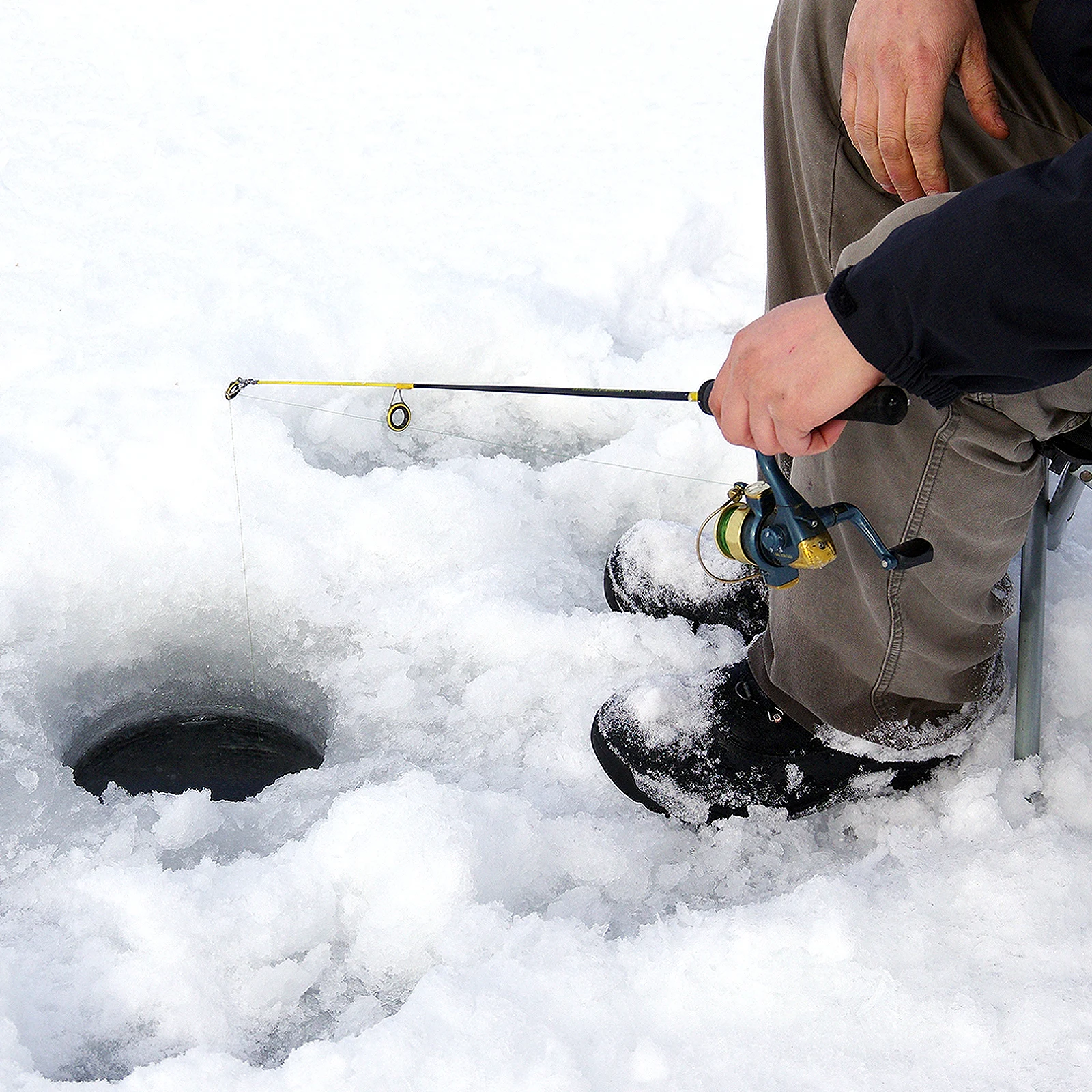 Man sitting fishing with ice fishing pole