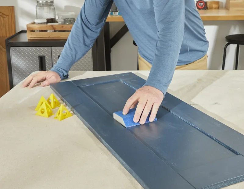 A man sands the cabinets again