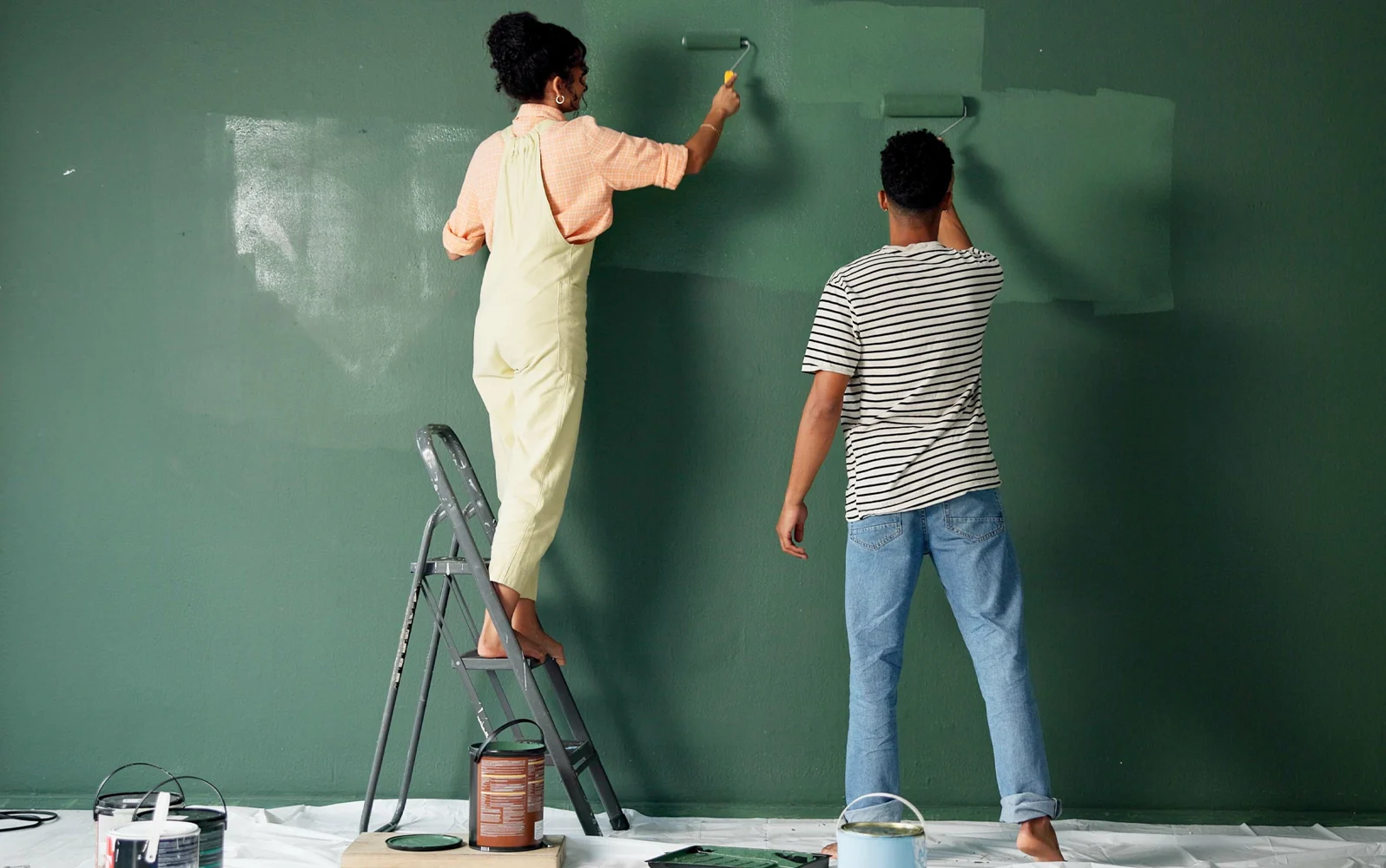 Image of a couple painting a room a hunter green colour.