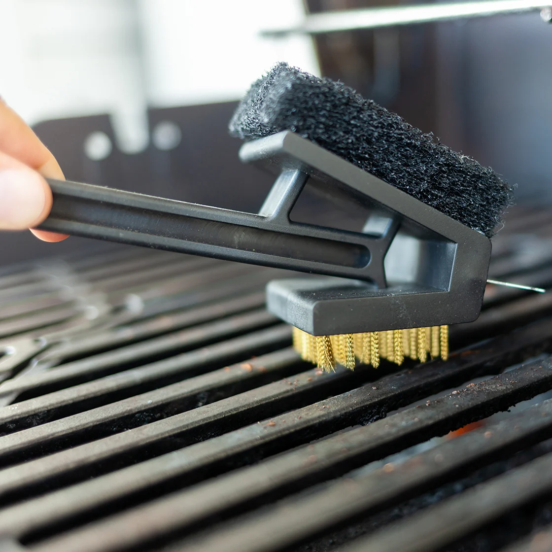 Quelqu'un nettoie un gril avec une brosse.