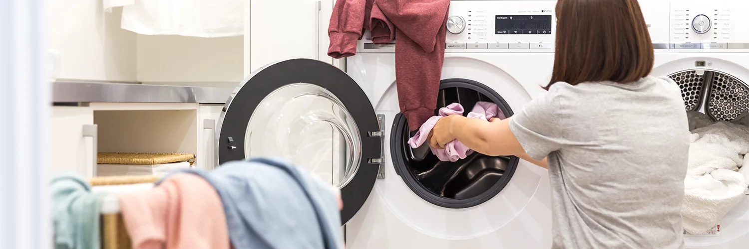 1500x500 Someone putting clothes into the dryer