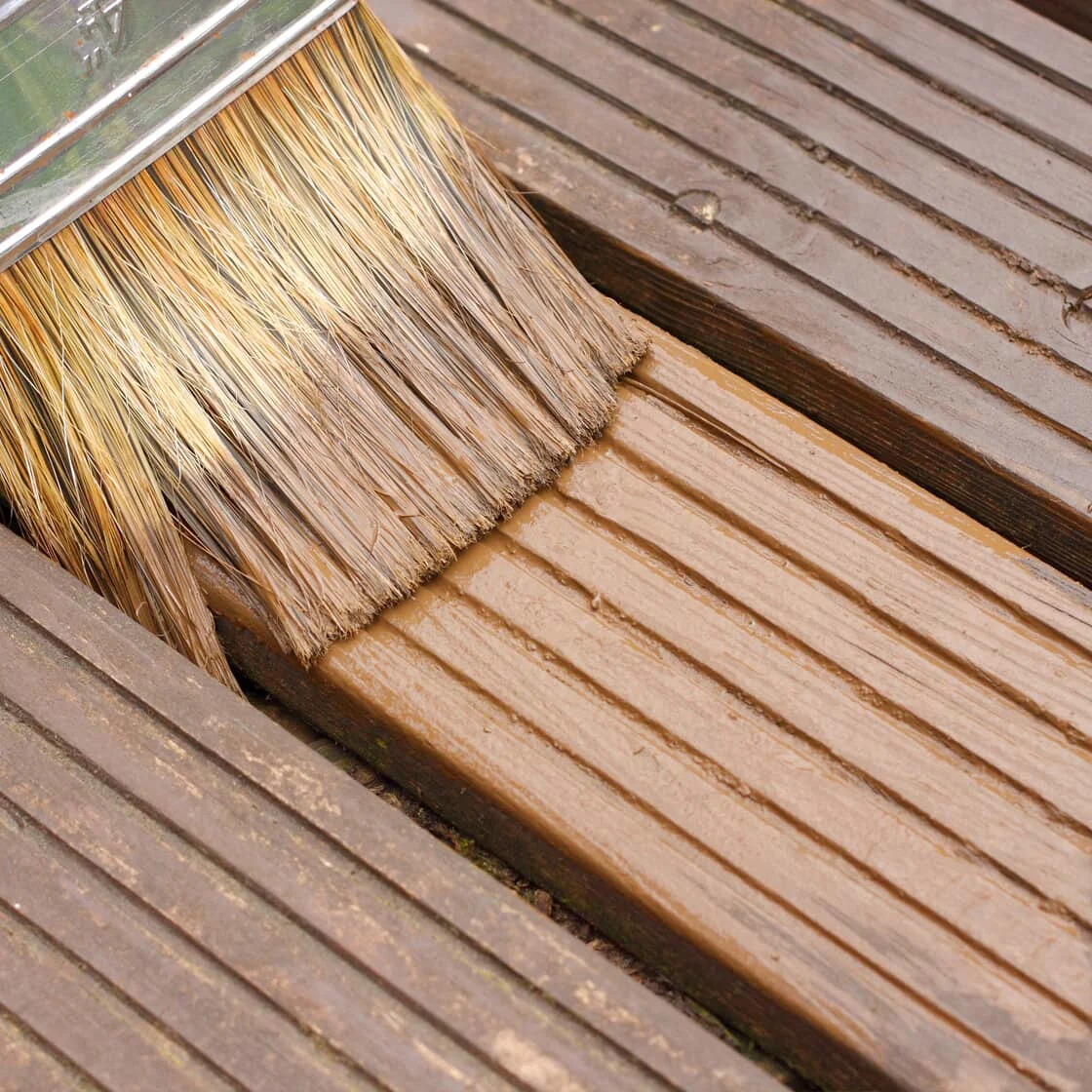Closeup of stain being brushed onto a deck
