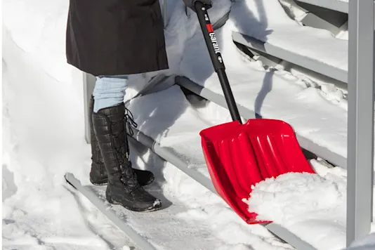 Image d’une femme déblayant la neige des marches.