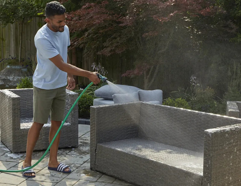 Un homme rinçant les mobilier de terrasse