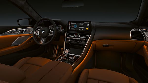 Interior view of a luxury BMW car featuring a modern dashboard with an infotainment screen, leather seats, ambient lighting, and a sleek steering wheel.
