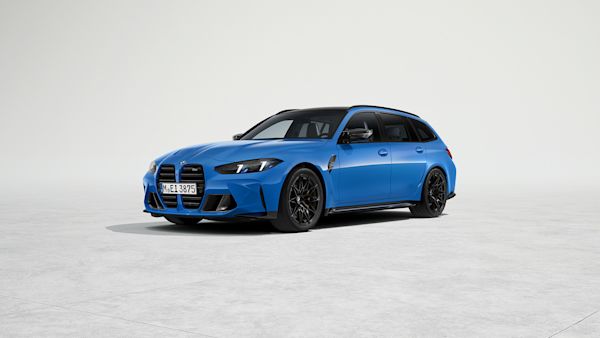 Blue BMW M3 Touring car parked on a concrete surface with a plain light gray background.