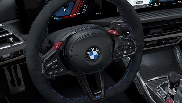 Interior view of a BMW car showing the steering wheel with the BMW logo, dashboard with digital displays, and gear shift.