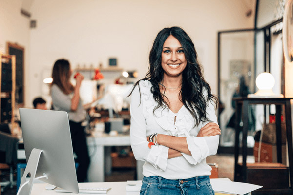 Young woman entrepreneur standing in front of her desk. 