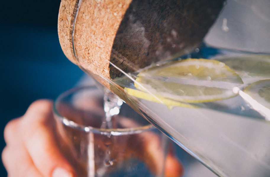 Water pouring into a cup with lemon and cork top 