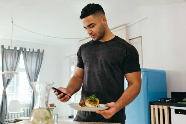 man with smartphone and meal indoors