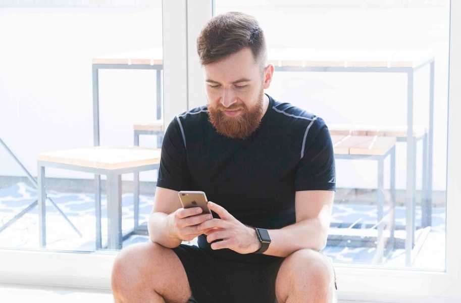 Man with beard, sitting with phone 