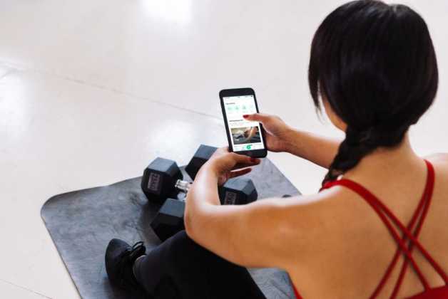 woman on yoga mat with weights and smartphone