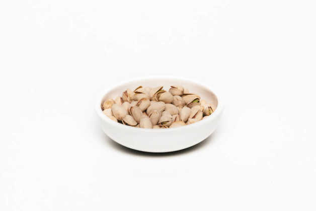 Pistachios in shell and in white bowl