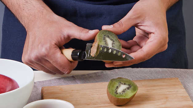Kiwi being sliced with knife